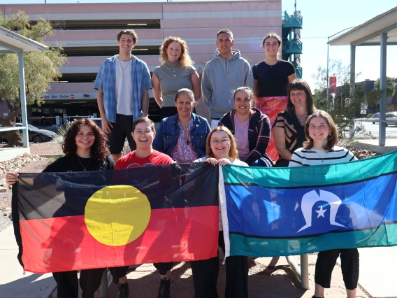 Aboriginal students on an Aurora Foundation U.S. Study Tour pose outside of NNI with Aboriginal and Torres Strait Islander flags