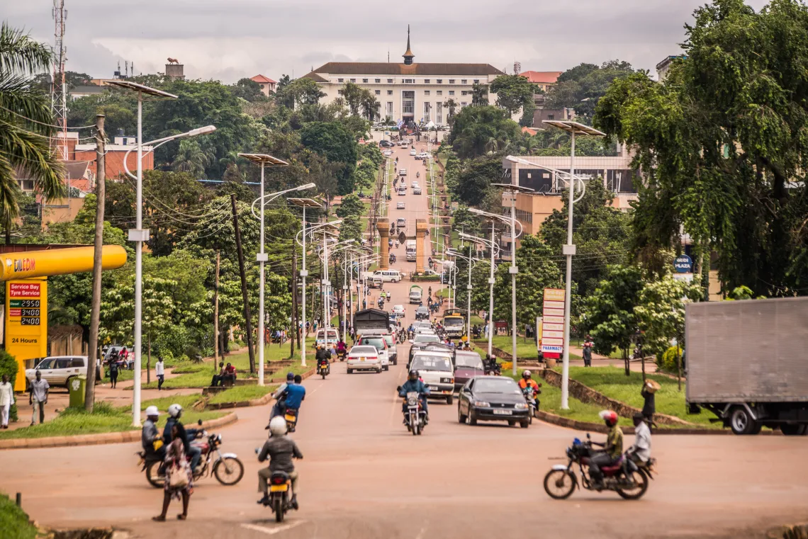 The white building that houses the Parliament of Uganda sits at the end of a busy road at the top of a hill.