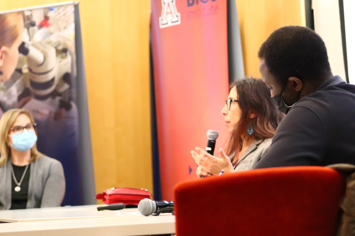 Stephanie Carroll and Ibrahim Garba speak from behind a table as BIO5 Institute Director Jennifer Barton looks on.