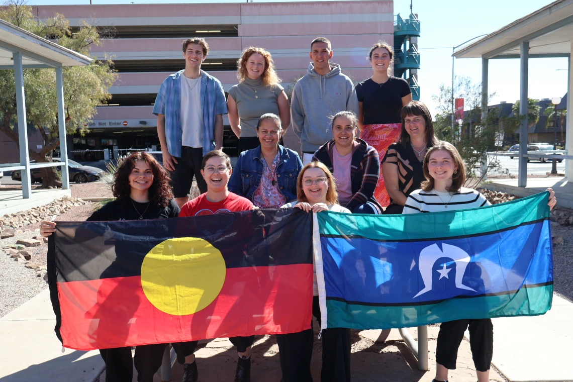 Aboriginal students on an Aurora Foundation U.S. Study Tour pose outside of NNI with Aboriginal and Torres Strait Islander flags