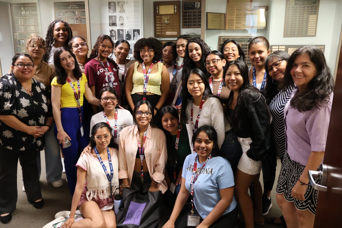 SUSI students pose with program manager Marcela Vasquez-Leon and NNI staff in front of a trophy case belonging to the U of A School of Journalism