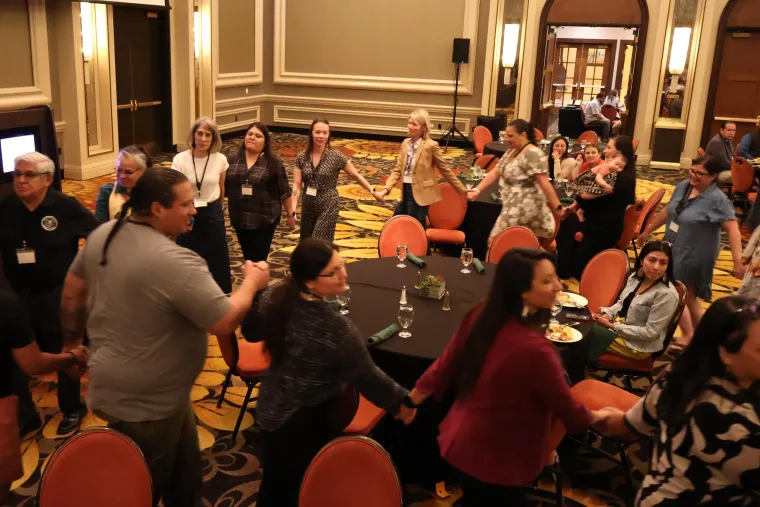 Attendees hold hands and dance during a traditional Akimel O'odham performance by Chi'Chino Spirit.