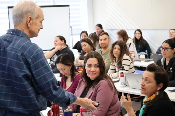 Stephen Cornell holds a microphone as a student offers a comment during JIT 2024.