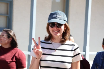 Study tour participant in a baseball cap that reads "New York" flashes the peace sign with one hand.