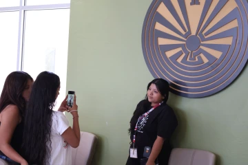 A student poses next to a large metal depiction of the Man in the Maze symbol